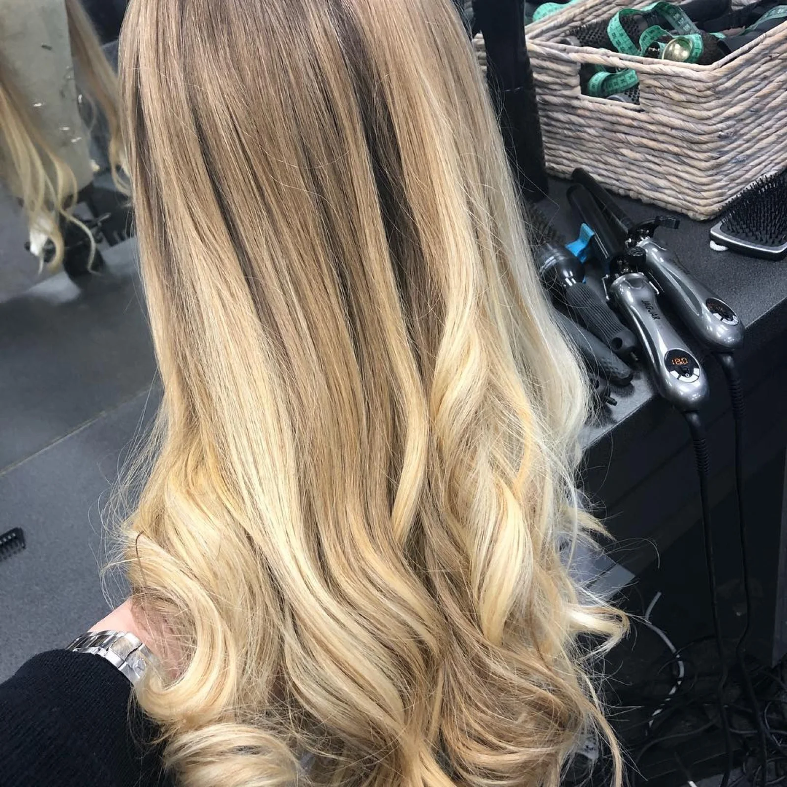 Perruque en cheveux naturels au balayage blond, vue de dos au poste de travail du salon