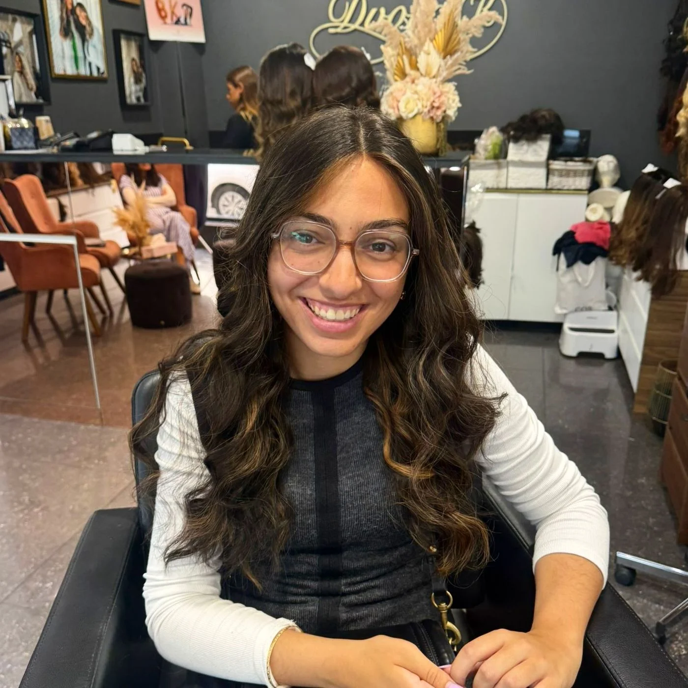 Cliente souriante avec lunettes portant une perruque bouclée en cheveux naturels