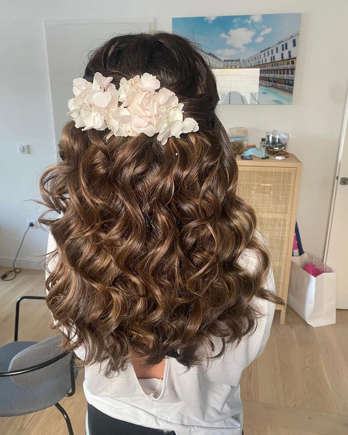 Perruque brune coiffée en demi-attache bouclée ornée de fleurs pour une mariée, vue de dos, Dvora K
