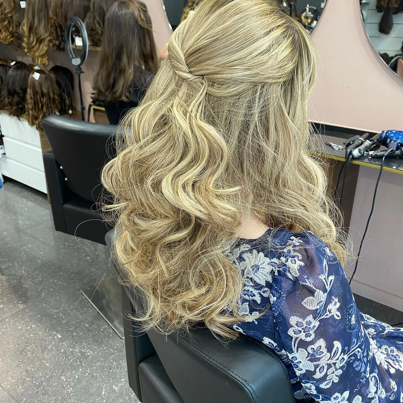 Perruque blonde ondulée coiffée en demi-attache torsadée, vue de dos au salon, Dvora K
