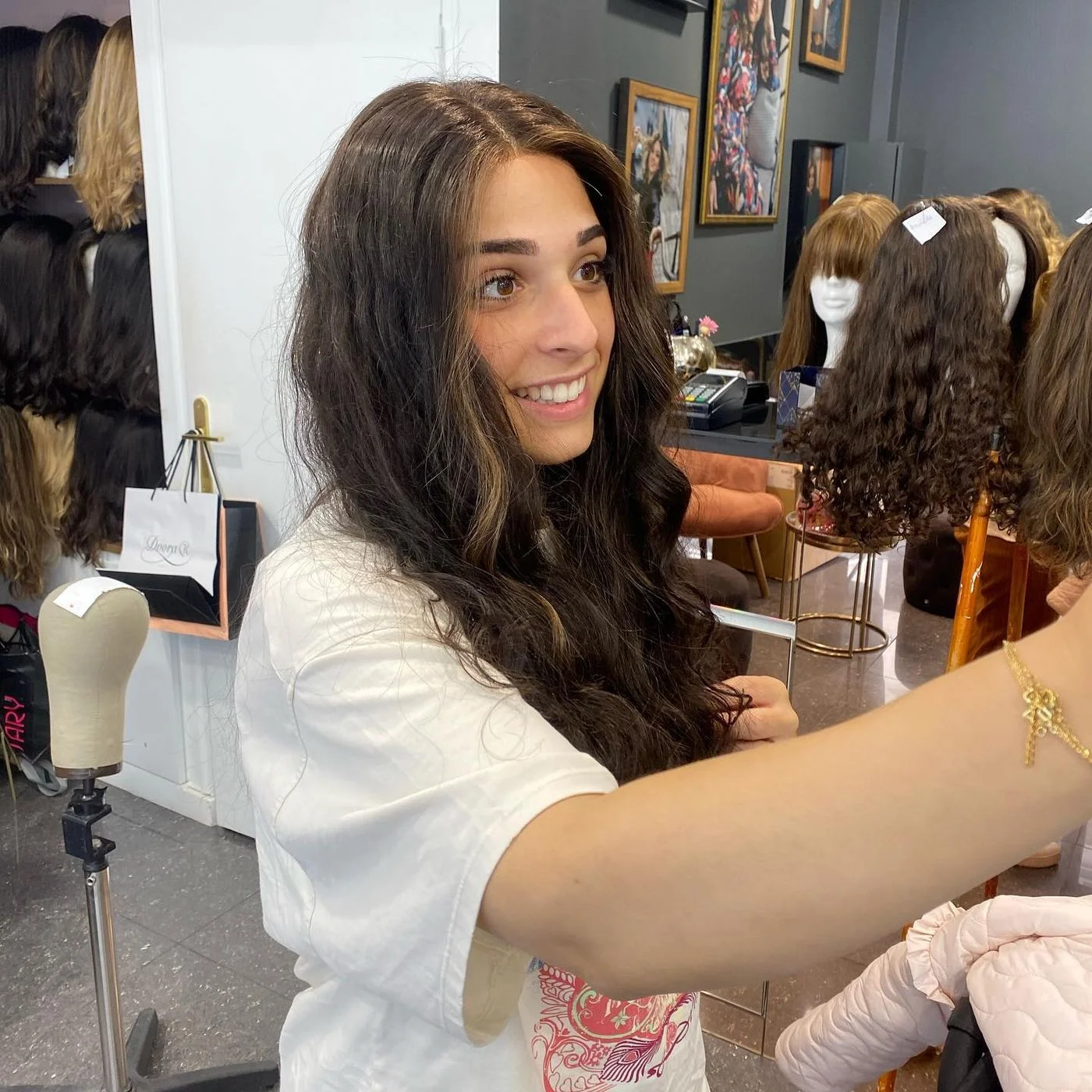 Les mains de la perruquière examinent la chevelure d'une perruque portée par une cliente au salon
