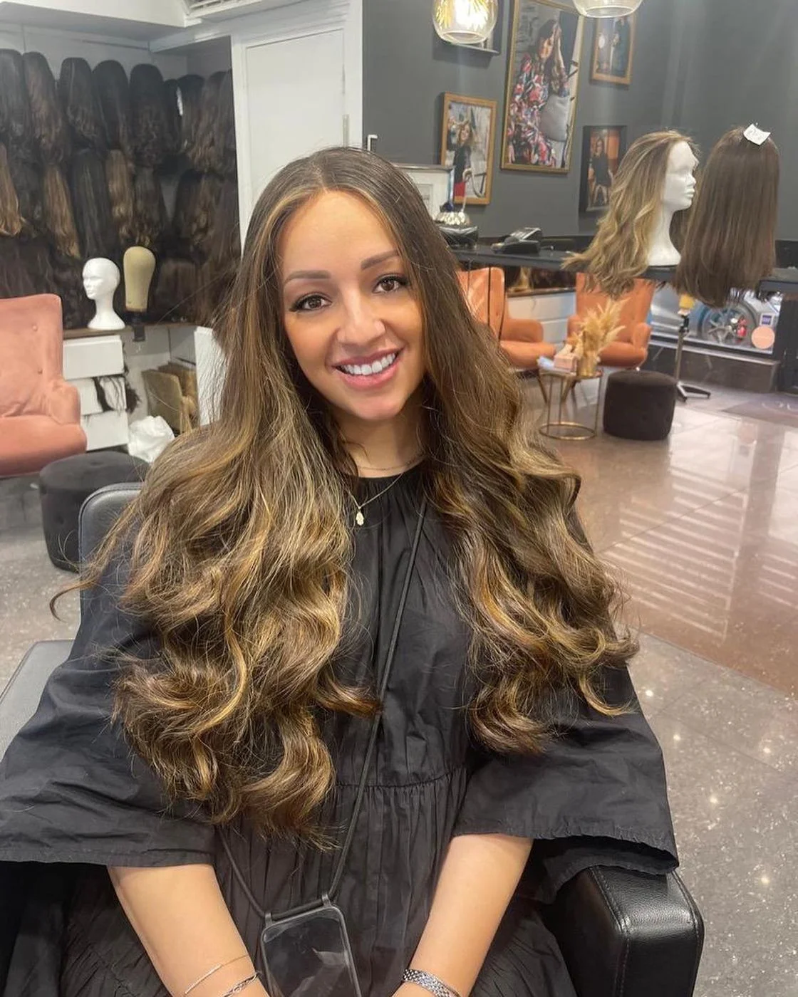 Cliente souriante portant une perruque longue ondulée en cheveux naturels