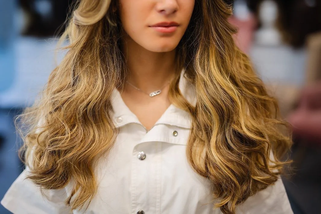Longue chevelure ondulée blond-brun en cheveux naturels, portée avec une chemise blanche, Dvora K