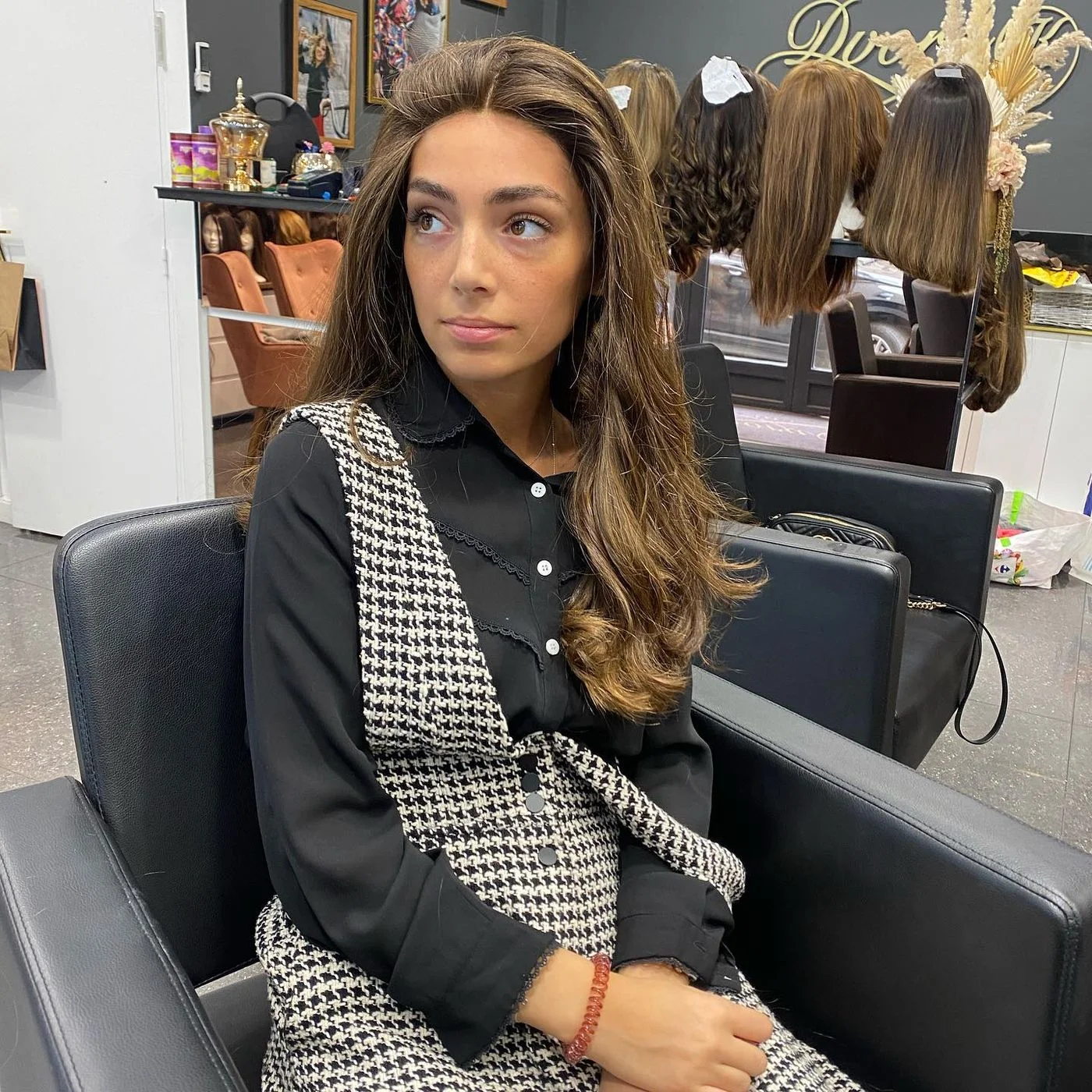 Perruque mi-longue brune en cheveux naturels portée avec une veste pied-de-poule
