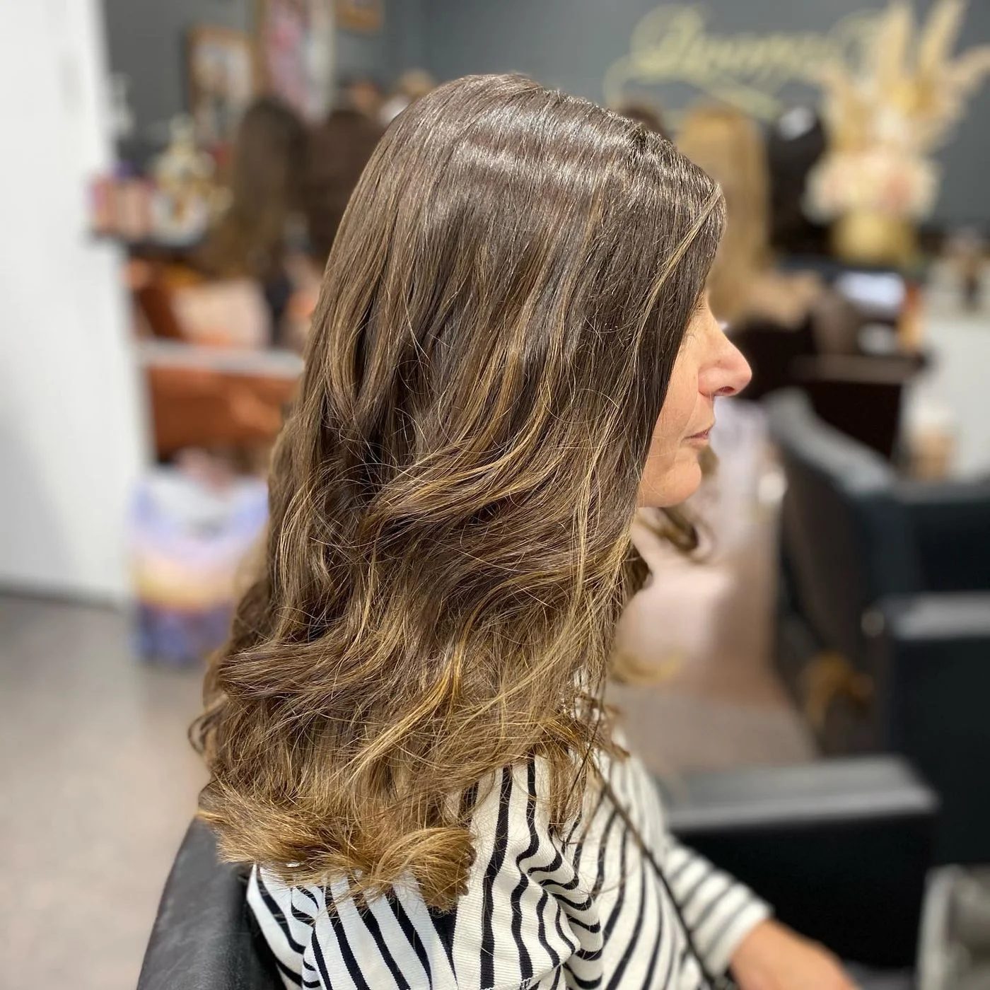 Profil d'une femme mûre portant une perruque mi-longue châtain aux reflets méchés, coiffée au salon