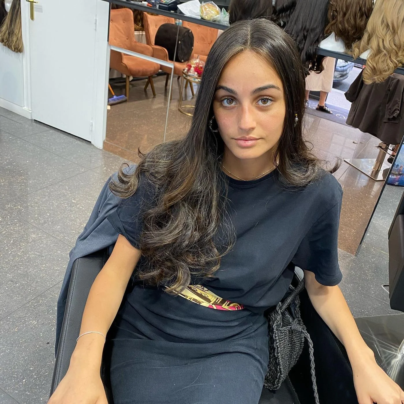 Cliente en cape d'essayage dans le salon, perruques en arrière-plan