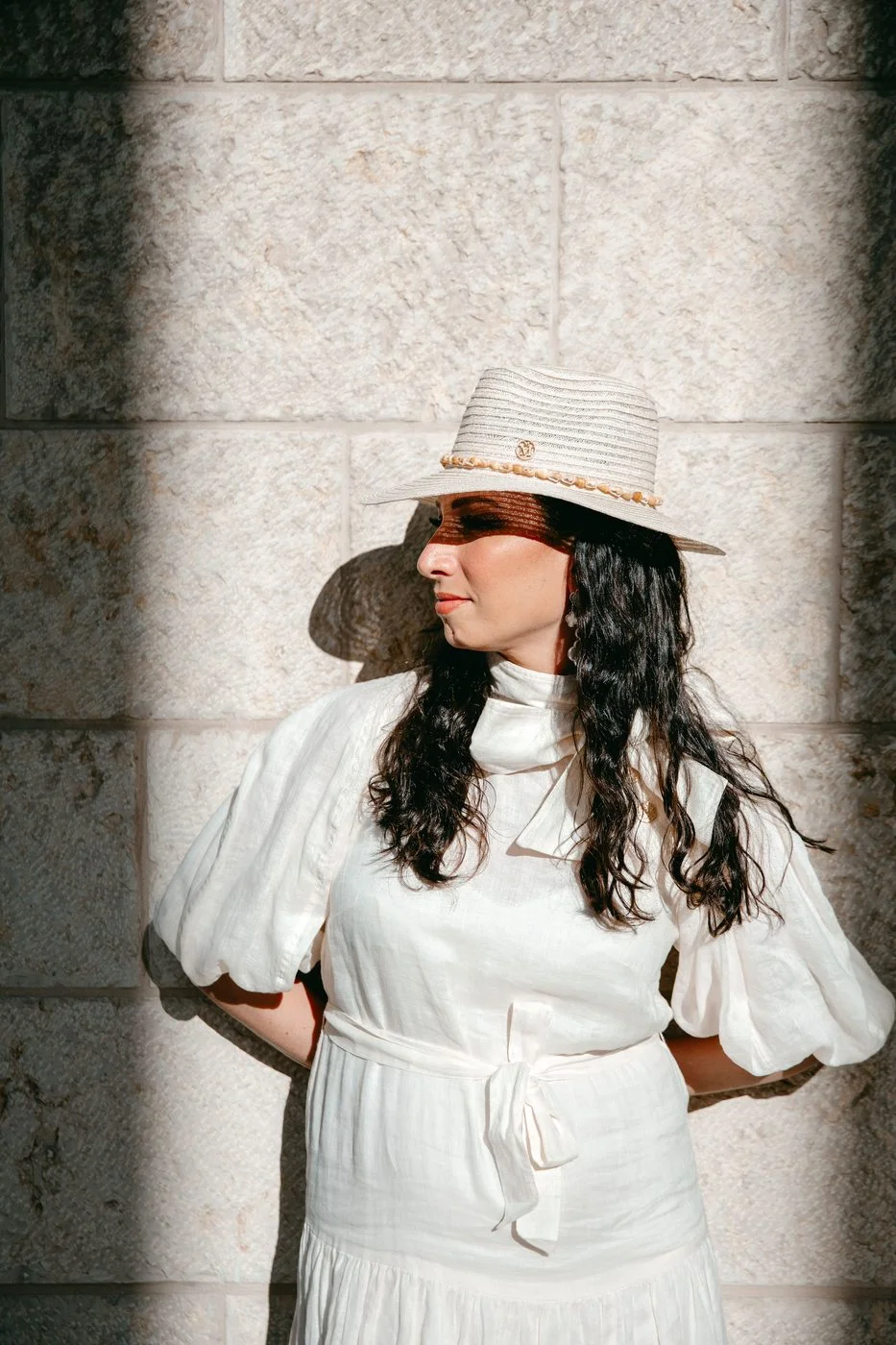 Perruque noire longue et bouclée en cheveux naturels, portée en robe blanche