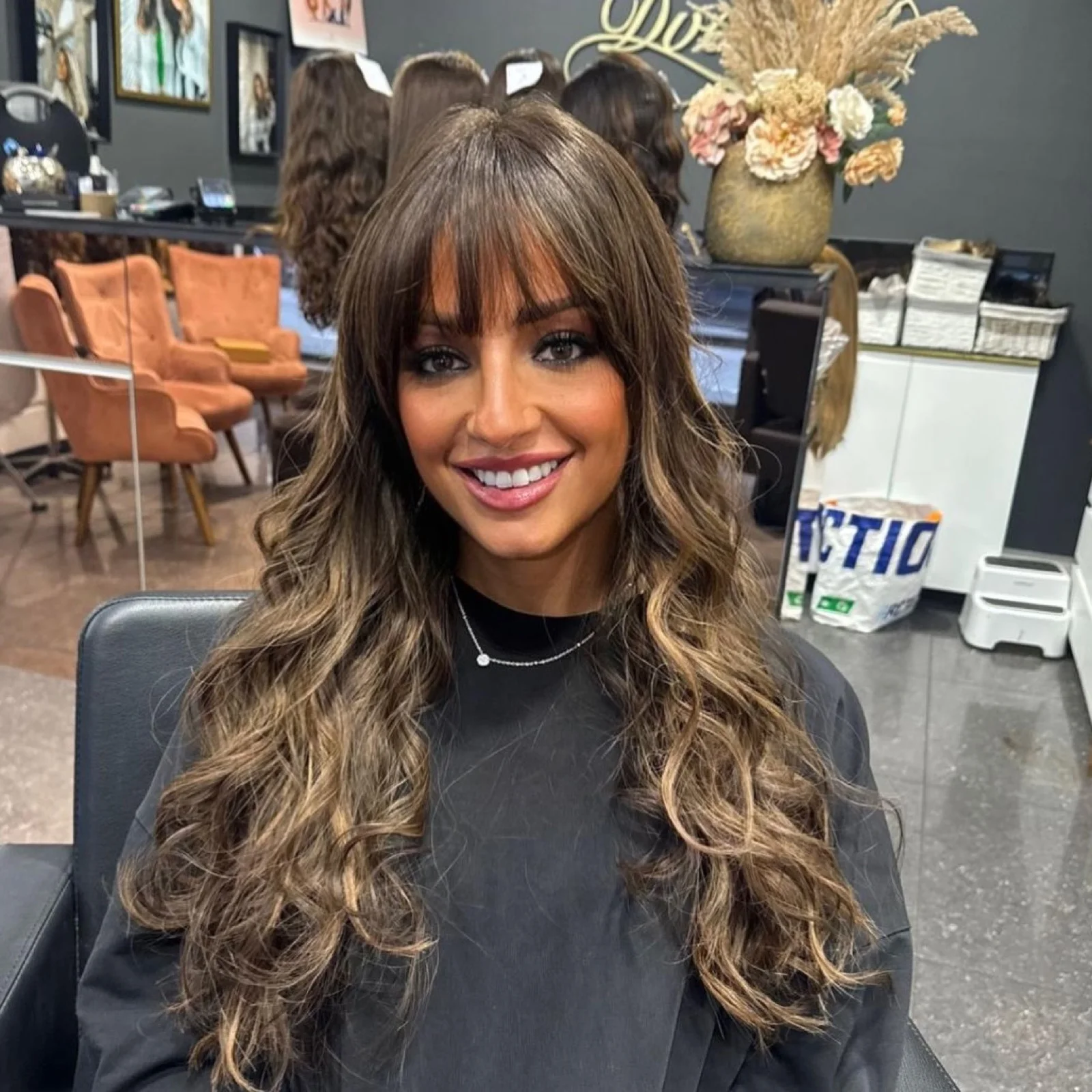 Cliente souriante portant une perruque brune avec frange
