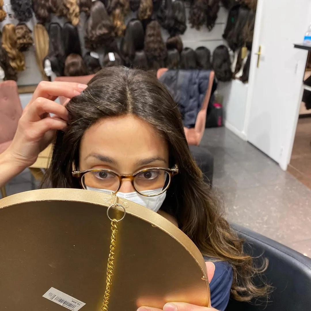 Au salon, la coiffeuse ajuste la raie pendant que la cliente se regarde dans le miroir